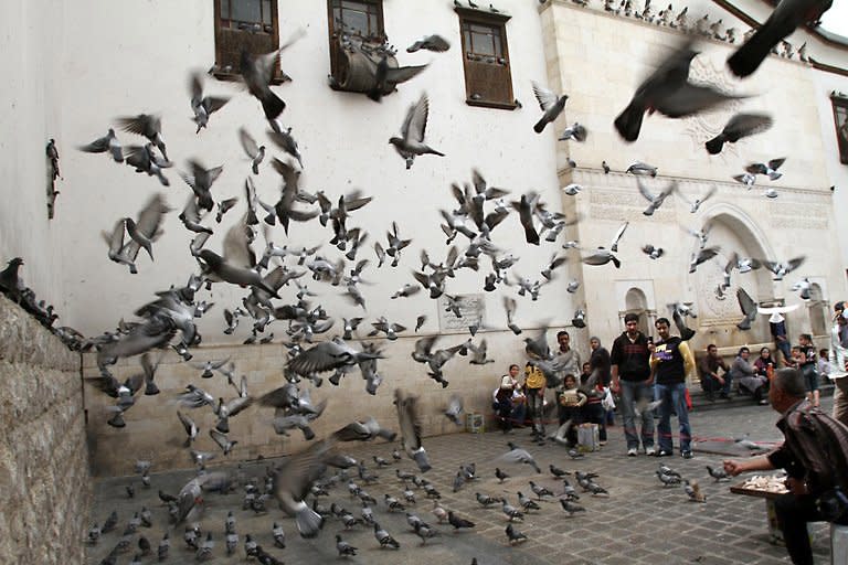 People gather as a man feeds pigeons flying outside the Omayyad Mosque in the old city of Damascus on April 2. Protests for greater freedoms spread Wednesday to Aleppo, Syria's second city, where hundreds of university students clashed with police and a smaller protest took place in the capital, rights activists told AFP by telephone