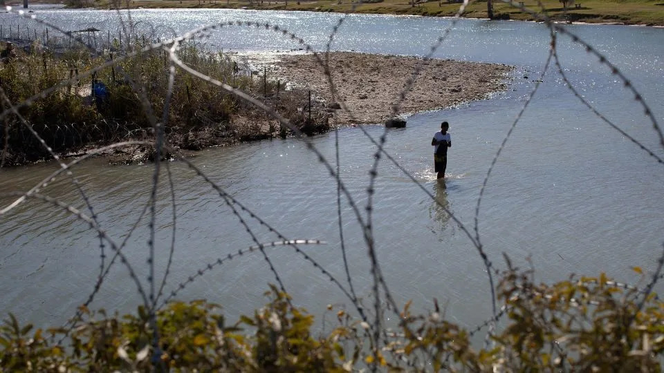 A man crosses the Rio Grande River from Mexico to collect clothing and other items left on the Texas banks of Shelby Park at the US-Mexico border in Eagle Pass, Texas, on January 12, 2024. - Kaylee Greenlee Beal/Reuters