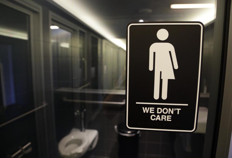 FILE - This Thursday, May 12, 2016, file photo, shows a sign outside a restroom at 21c Museum Hotel in Durham, N.C. The Associated Press has determined that North Carolina's law limiting LGBT protections will cost the state more than $3 billion in lost business over a dozen years.That's despite Republican assurances that the "bathroom bill" isn't hurting the economy. (AP Photo/Gerry Broome, File)