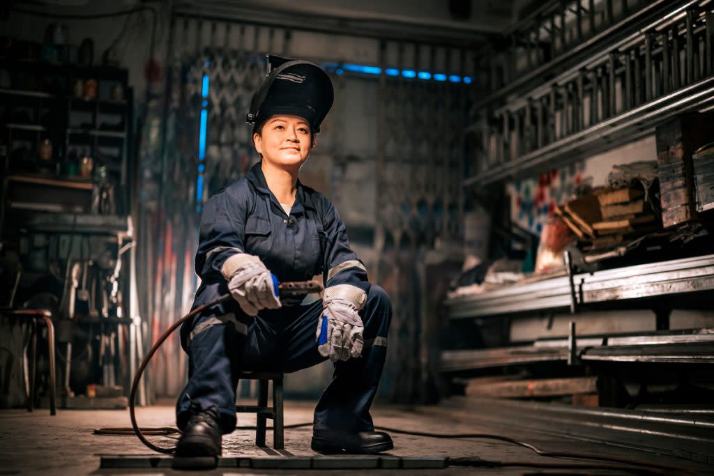 A female welder poses for a portrait in her workshop. 