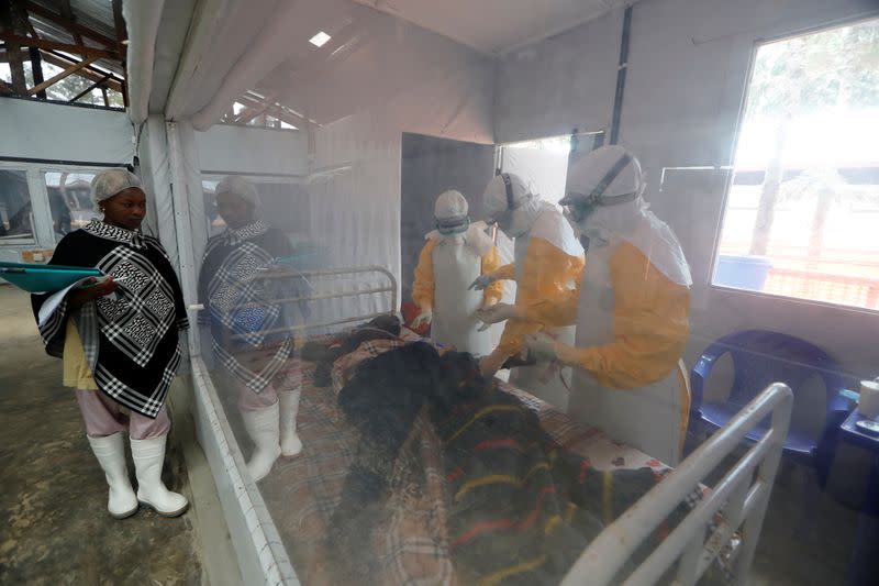 FILE PHOTO: Moise Vaghemi, 33, (C) an Ebola survivor who works as a nurse, cares for a patient who is suspected to be suffering from Ebola, inside the Biosecure Emergency Care Unit (CUBE) at the Ebola treatment centre in Katwa