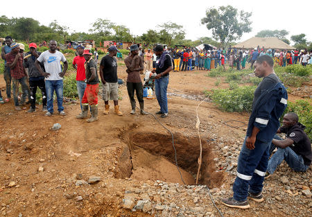 People gather over a shaft as retrieval efforts proceed for trapped illegal gold miners in Kadoma, Zimbabwe, February 15, 2019, REUTERS/Philimon Bulawayo