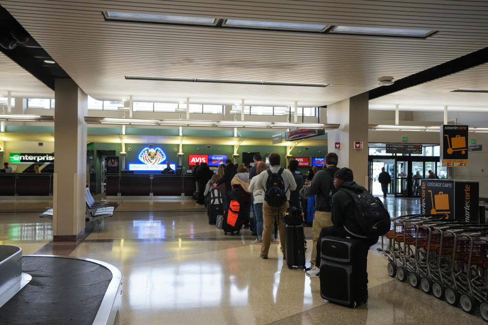 People wait in line for a rental car at the Des Moines International Airport on Monday, Record travel is forecast for Thanksgiving week.