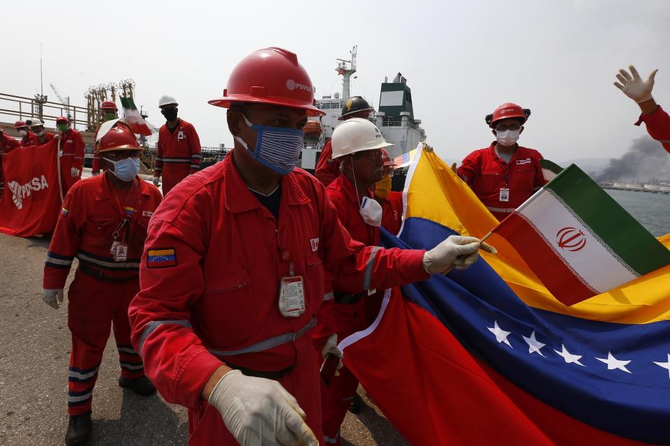 Un trabajador petrolero venezolano que sostiene una pequeña bandera de Irán asiste a una ceremonia el lunes 25 de mayo de 2020 por la llegada del buque iraní Fortune, en la refinería El Palito cerca de Puerto Cabello, Venezuela. (AP Foto/Ernesto Vargas)