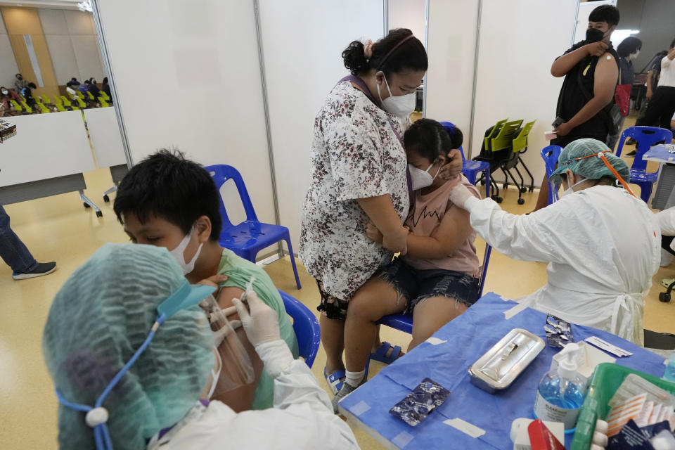 A mother tries to comfort her child before receiving the Pfizer-BioNTech COVID-19 vaccine at a hospital in Bangkok, Thailand, Tuesday, Sept. 21, 2021. Bangkok Metropolitan Administration started inoculated 12-18 year old students Tuesday as part of its attempt to reopen on-site schools. (AP Photo/Sakchai Lalit)