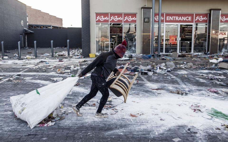 A suspected looter pulls a sack along the ground outside a vandalised mall in Vosloorus, on the outskirts of Johannesburg - MARCO LONGARI /AFP 