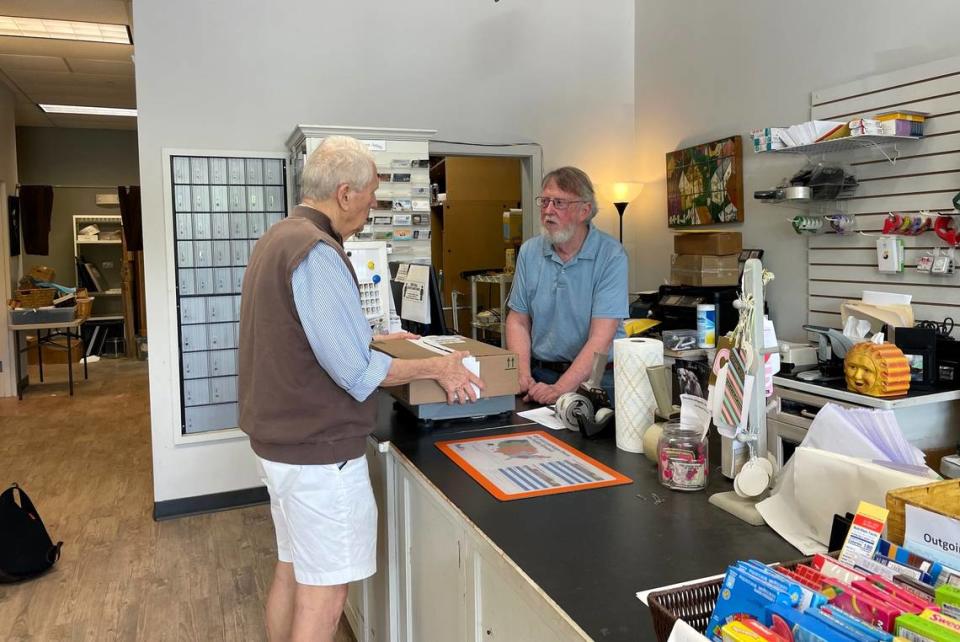 Bob Gunn, owner of Stray’s Ship-and-Shop in Southern Village, advises a customer on the best way to ship a package. Gunn has operated the store, which also adopts out rescue dogs and features local artists, for 12 years. He will close April 27.