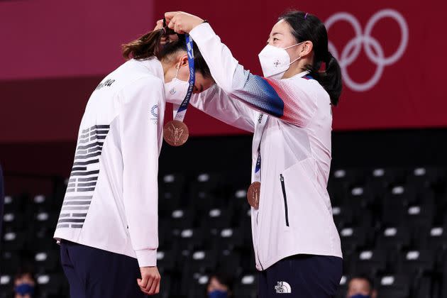 Bronze medalists Kim Soyeong, left, and Kong Heeyong of Team South Korea place their medals on each other during the ceremony for the women’s doubles badminton event on Aug. 2. (Photo: Lintao Zhang via Getty Images)