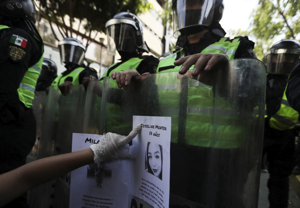 FILE - In this June 7, 2020 file photo, a demonstrator sticks a flyer of a women who was a victim of violence on the riot shield of police officer outside Mexico City's security headquarters during a protest amid the COVID-19 pandemic in Mexico City. New government figures show the number of homicides in Mexico has grown during the new coronavirus pandemic, including a 9.2% spike in killings of women, according to data released Monday, July 20. (AP Photo/Fernando Llano, File)