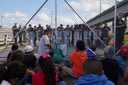 A group of migrants who returned to Mexico to await their U.S. asylum hearing block the Puerta Mexico international border crossing bridge