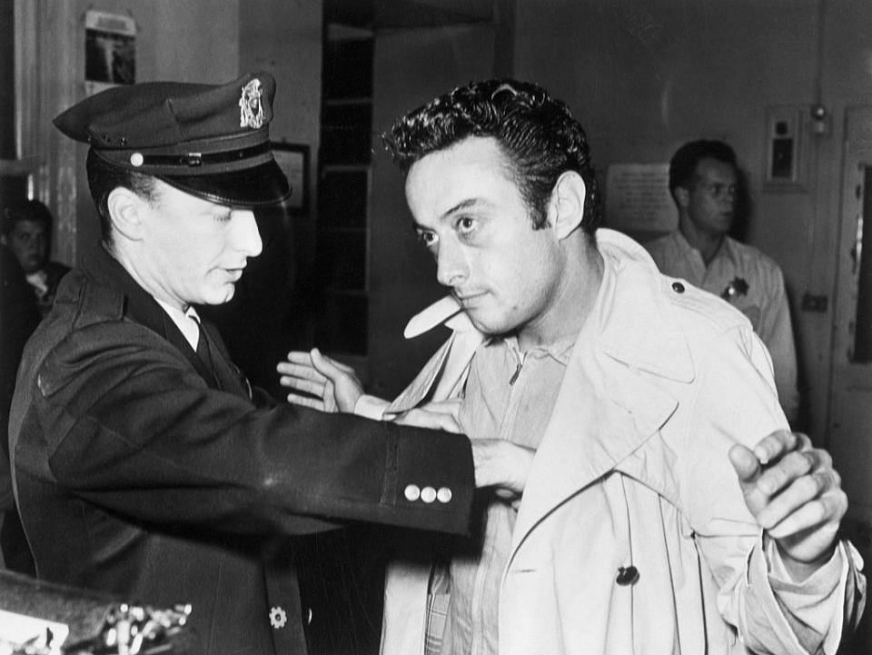 Lenny Bruce getting searched by a police officer after being arrested