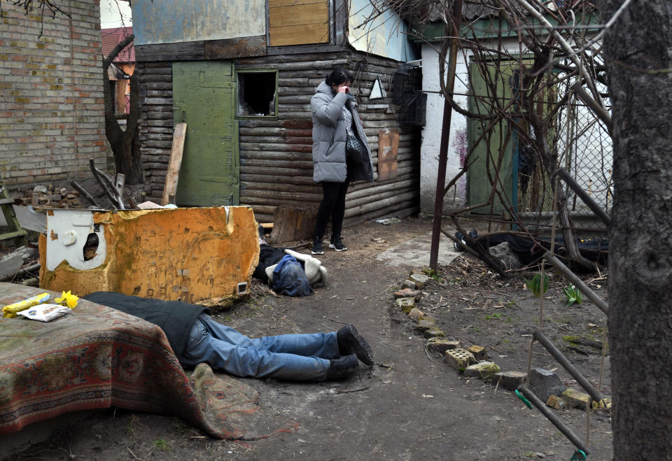 The bodies of Sergei Guryanova and his brother-in-law Roman, who had both been shot in the head, lie in a courtyard as Irina, the wife of Sergei and sister of Roman, quietly weeps. 