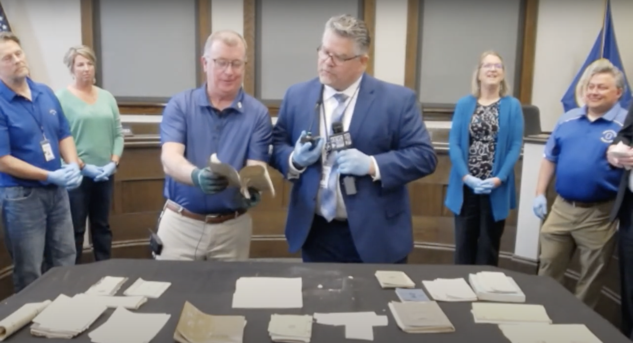 Owatonna Public Schools Superintendent Jeff Elstad and Director of Facilities, Infrastructure and Security Bob Olson examine documents hidden in a 1920 time capsule. / Credit: Owatonna Public Schools via YouTube