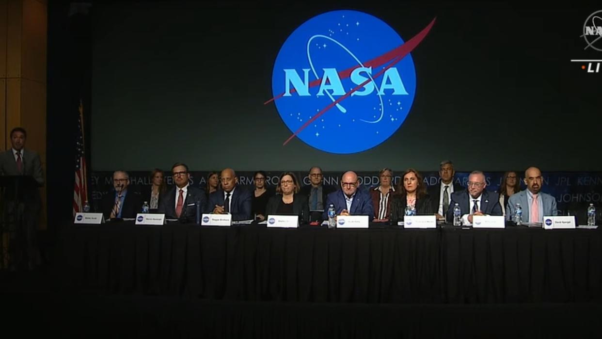  a group of people in suits at a table with a nasa logo 