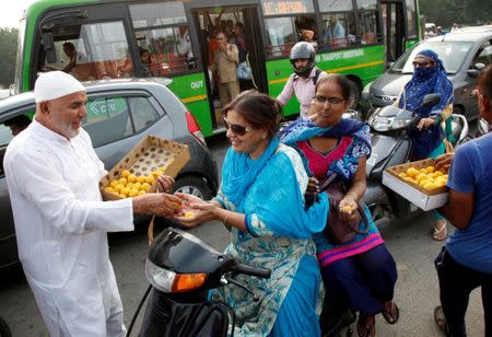 A man distributes sweets to commuters to celebrate after India on Thursday said it had conducted targeted strikes across the de facto frontier in Kashmir region, in Chandigarh, India, September 30, 2016. REUTERS/Ajay Verma