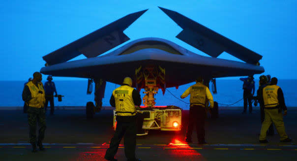A US Navy X-47B Unmanned Combat Air System aircraft is towed into the hanger bay aboard the aircraft carrier USS George H.W. Bus