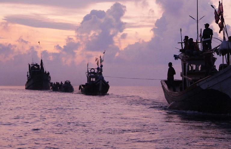 An Acehnese fishing boat (right) tows a boat of Rohingya migrants off the coast near the city of Geulumpang, in Indonesia's East Aceh district of Aceh province, on May 20, 2015