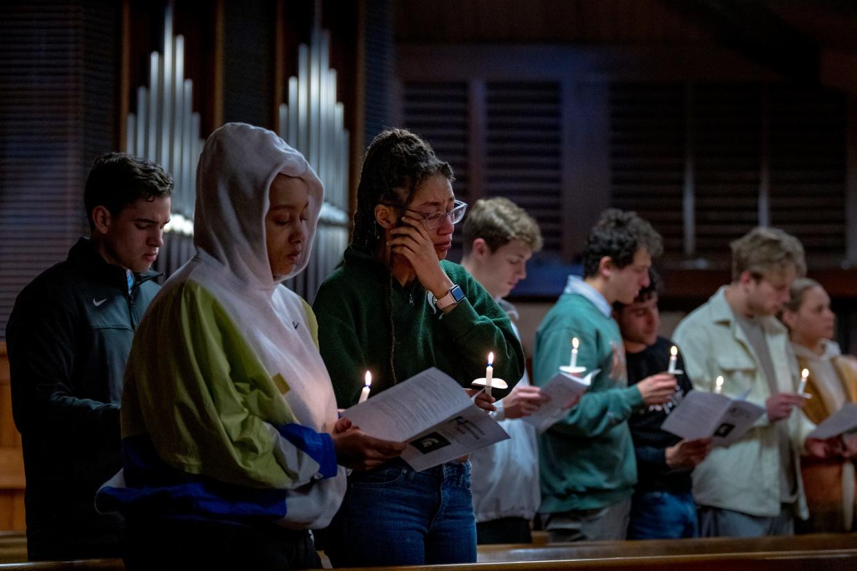 Students hold candles and wipe away tears at a vigil for victims of the Michigan State University shooting