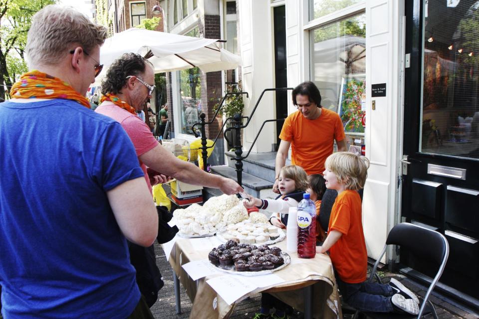 Children sell their homemade food at the annual free market during festivities marking King's Day in Amsterdam, Netherlands, Saturday, April 26, 2014. The Dutch celebrate the first ever King's Day, a national holiday held in honor of the newly installed monarch, King Willem Alexander. King's Day replaces the traditional Queen's Day. (AP Photo/Margriet Faber)