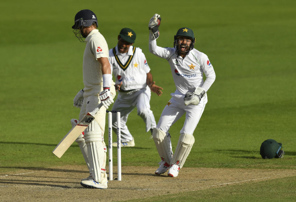 Pakistan's wicketkeeper Mohammad Rizwan, right, celebrates after taking the catch to dismiss England's captain Joe Root, left, during the second day of the first cricket Test match between England and Pakistan at Old Trafford in Manchester, England, Thursday, Aug. 6, 2020. (Dan Mullan/Pool via AP)