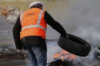 An employee of French state-owned railway company SNCF throws a tyre onto a burning barricade to block the entrance of the depot of the society SFDM near the oil refinery of Donges, France, May 25, 2016 in protest over proposed new labour laws. REUTERS/Stephane Mahe