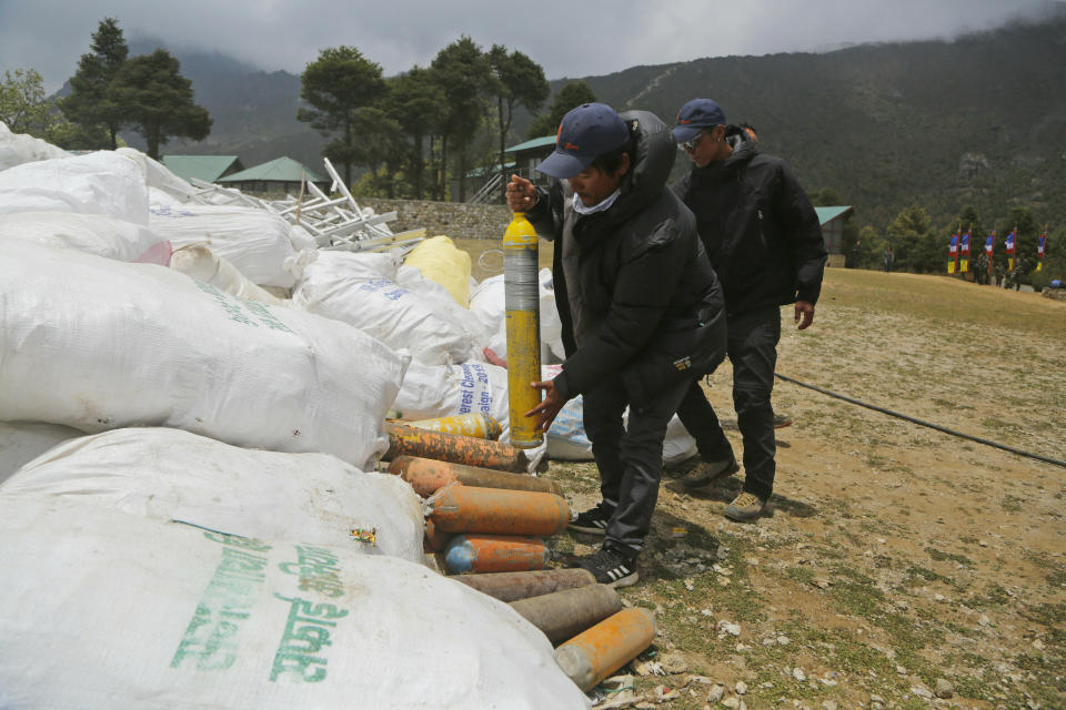 In this May 27, 2019 photo, members of garbage retrieval expedition pile up empty oxygen cylinders collected from Mount Everest in Namche Bajar, Solukhumbu district, Nepal. The record number of climbers on Mount Everest this season has left a cleanup crew grappling with how to clear away everything from abandoned tents to human waste that threatens drinking water. (AP Photo/Niranjan Shrestha)