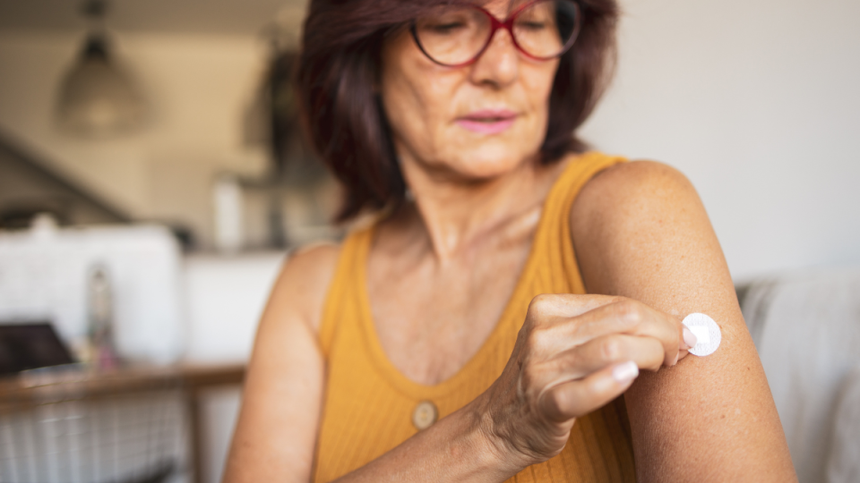 Woman uses a skin patch for hormone replacement therapy