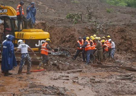 National Disaster Response Force (NDRF) personnel carry the body of a victim from the site of a landslide at Malin village, in the western Indian state of Maharashtra July 31, 2014. REUTERS/Shailesh Andrade