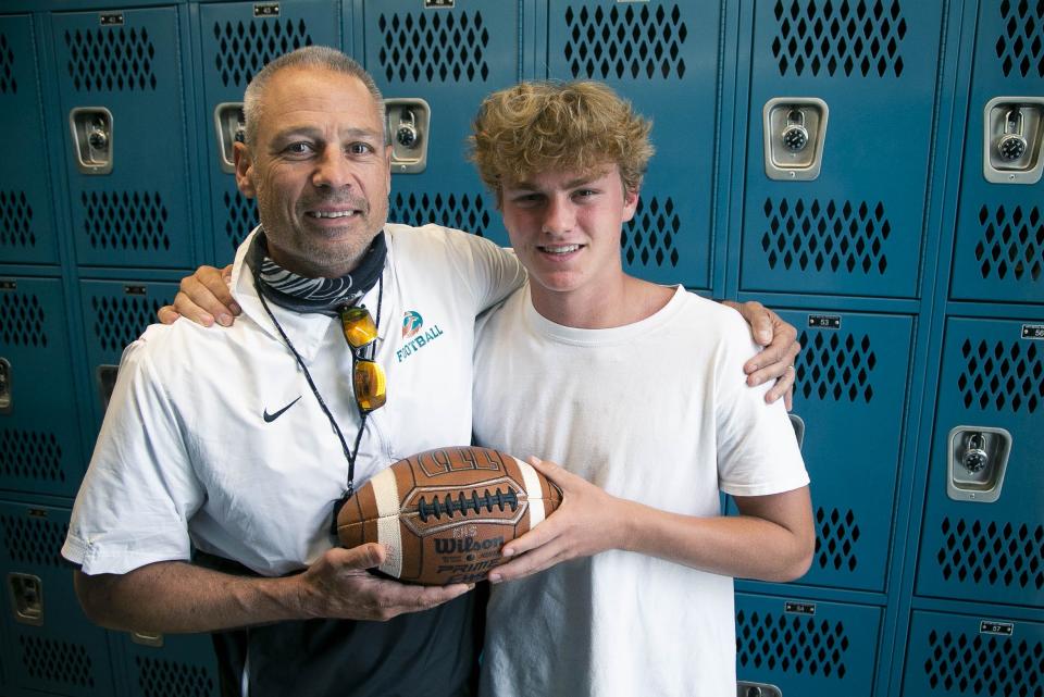 April 28, 2021; Mesa, AZ, USA; Eastmark High football coach Scooter Molander and his son, Mack, pose for a portrait at Eastmark High School on April 28, 2021.