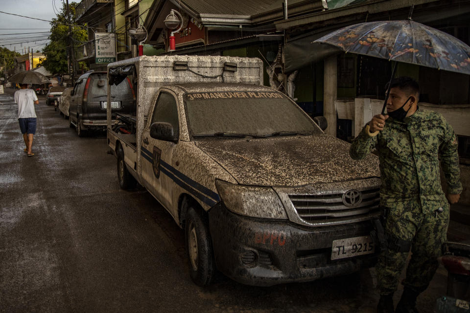 A policeman walks past a police vehicle covered in ash mixed with rainwater as Taal Volcano erupts on January 12, 2020 in Talisay, Batangas province, Philippines. (Photo: Ezra Acayan/Getty Images)