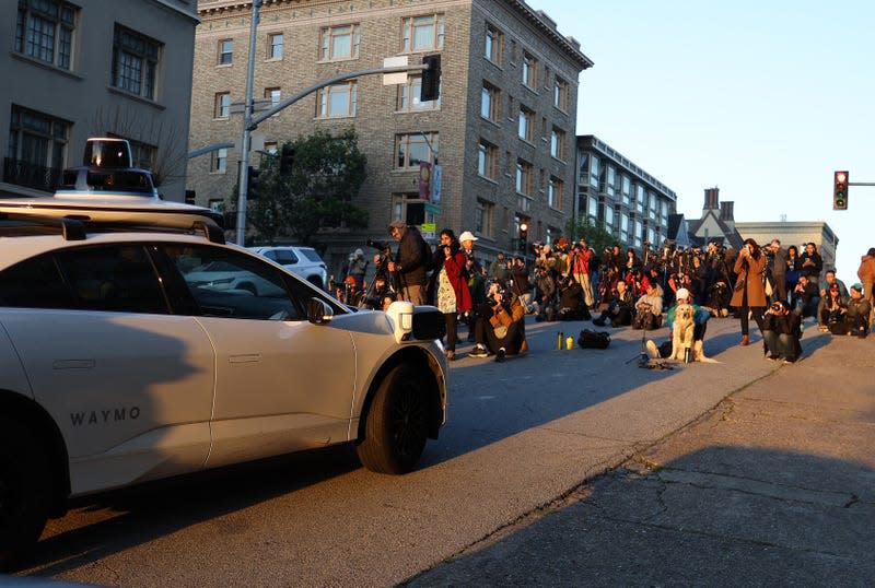 SAN FRANCISCO, CALIFORNIA - APRIL 09: A Waymo self-driving car stops while driving as people stand in the middle of the street to photograph the sunrise on April 09, 2024 in San Francisco, California. Dozens of people came out to see and photograph the biannual phenomenon dubbed “California Henge” when the sun falls perfectly between city blocks. - Photo: Justin Sullivan/Getty Images (Getty Images)