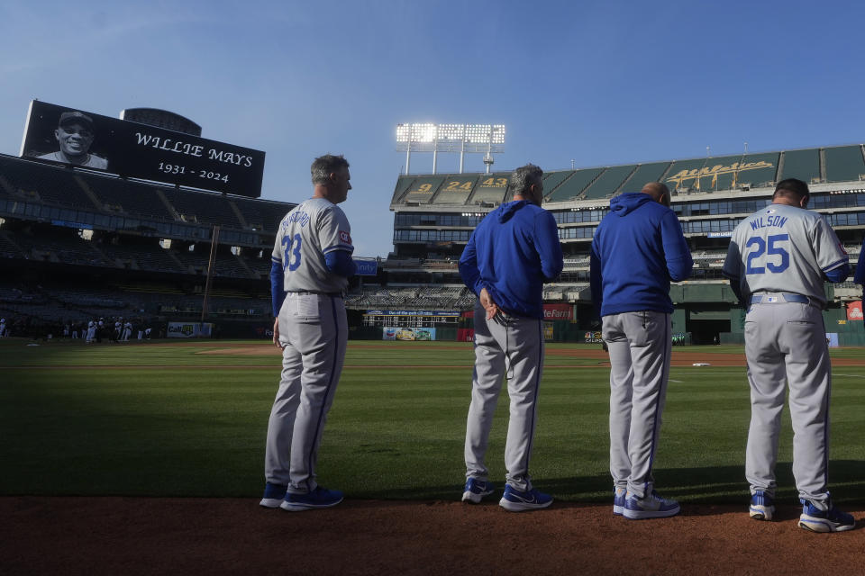 Kansas City Royals manager Matt Quatraro, left, observes a moment of silence with coaches and players for former MLB player Willie Mays before a baseball game between the Oakland Athletics and the Royals in Oakland, Calif., Tuesday, June 18, 2024. (AP Photo/Jeff Chiu)