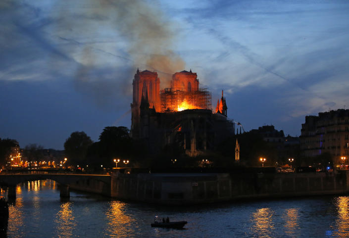 Firefighters tackle the blaze as flames and smoke rise from Notre Dame cathedral as it burns in Paris, Monday, April 15, 2019. Massive plumes of yellow brown smoke is filling the air above Notre Dame Cathedral and ash is falling on tourists and others around the island that marks the center of Paris. (Photo: Michel Euler/AP)
