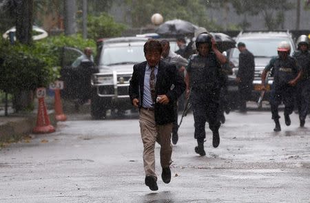 A Japanese official runs to take cover from rain after visiting the Holey Artisan Bakery and the O'Kitchen Restaurant, after the attack in Dhaka, Bangladesh, July 3, 2016. REUTERS/Adnan Abidi