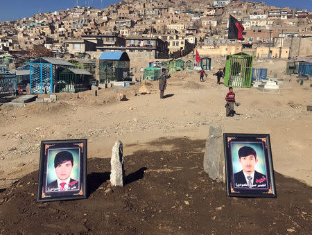 The photos of two brothers, who were killed during yesterday's suicide attack at a Shi'ite cultural centre, are seen on their graves in Kabul, Afghanistan. December 29, 2017. REUTERS/James Mackenzie
