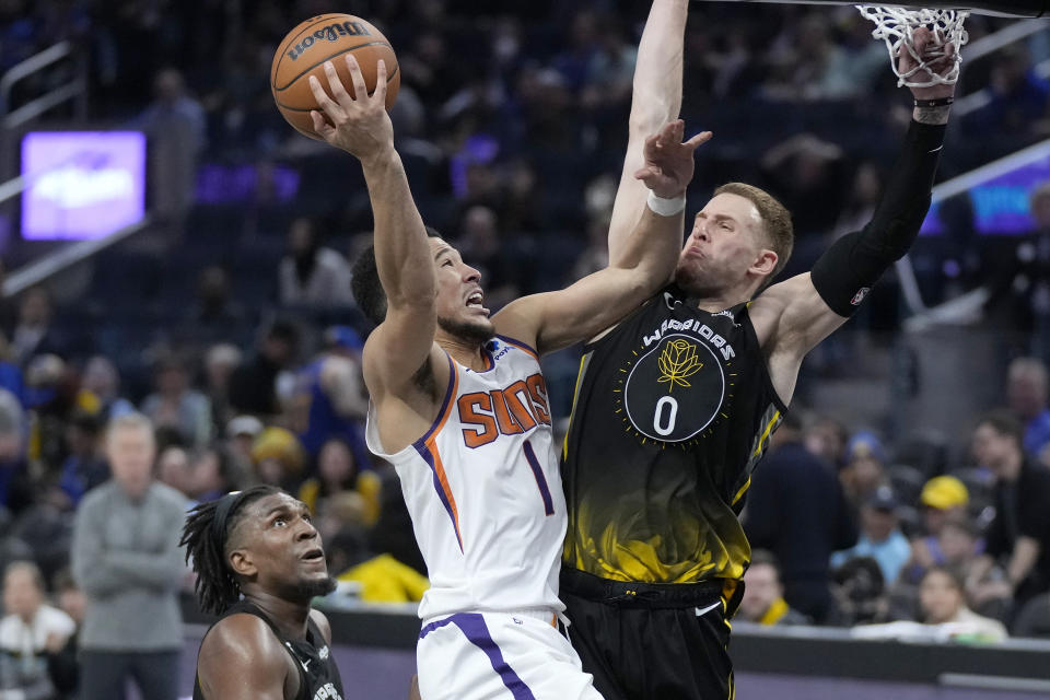 Phoenix Suns guard Devin Booker (1) is fouled by Golden State Warriors guard Donte DiVincenzo (0) during the second half of an NBA basketball game in San Francisco, Monday, March 13, 2023. (AP Photo/Jeff Chiu)