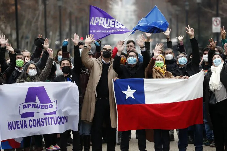 Manifestantes a favor de la aprobación de la nueva Constitución con una bandera chilena, el 6 de julio de 2022, en Santiago. La campaña para el plebiscito del 4 de septiembre para aprobar o rechazar el texto de una nueva Constitución comenzó este miércoles. (Photo by JAVIER TORRES / AFP)