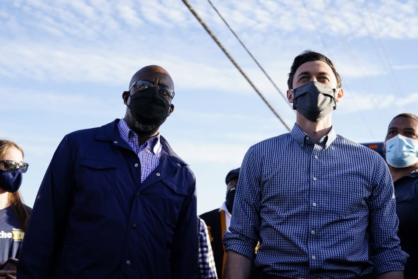 Georgia Democratic candidates for U.S. Senate Raphael Warnock, left, and Jon Ossoff, right, gesture toward a crowd during a campaign rally on Sunday, Nov. 15, 2020, in Marietta, Ga. (AP Photo/Brynn Anderson)