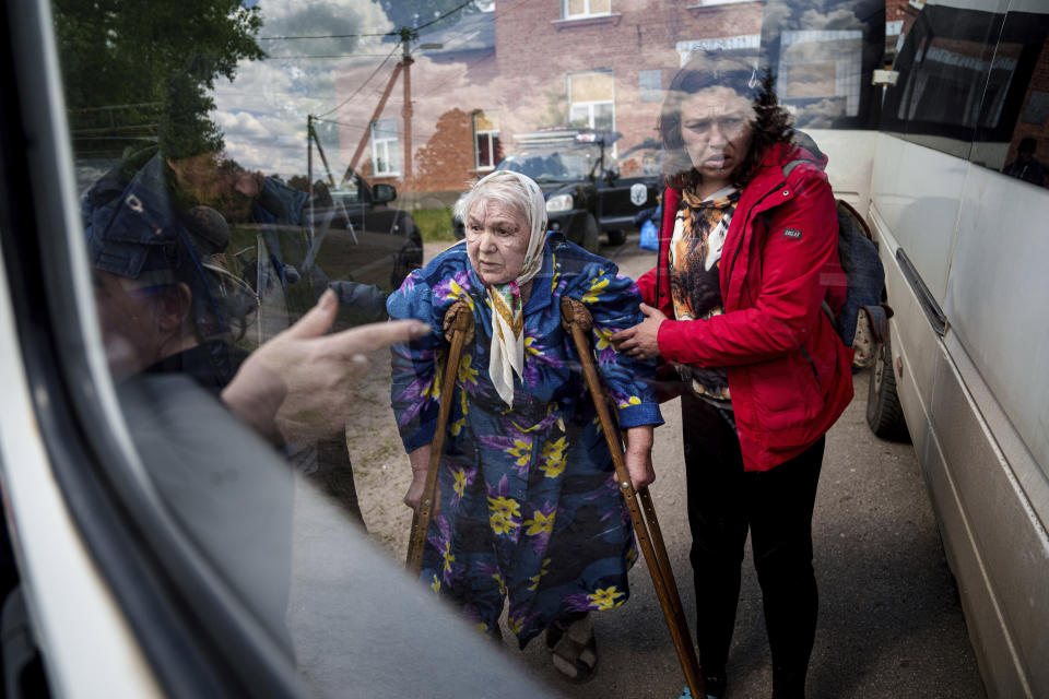 People help Liudmila, 85, to sit into a bus after their evacuation from Vovchansk, Ukraine, Sunday, May 12, 2024. Her husband was killed in their house after a Russian airstrike on the city. (AP Photo/Evgeniy Maloletka)