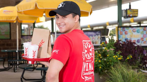 A Sonic carhop brings an order to a customer.