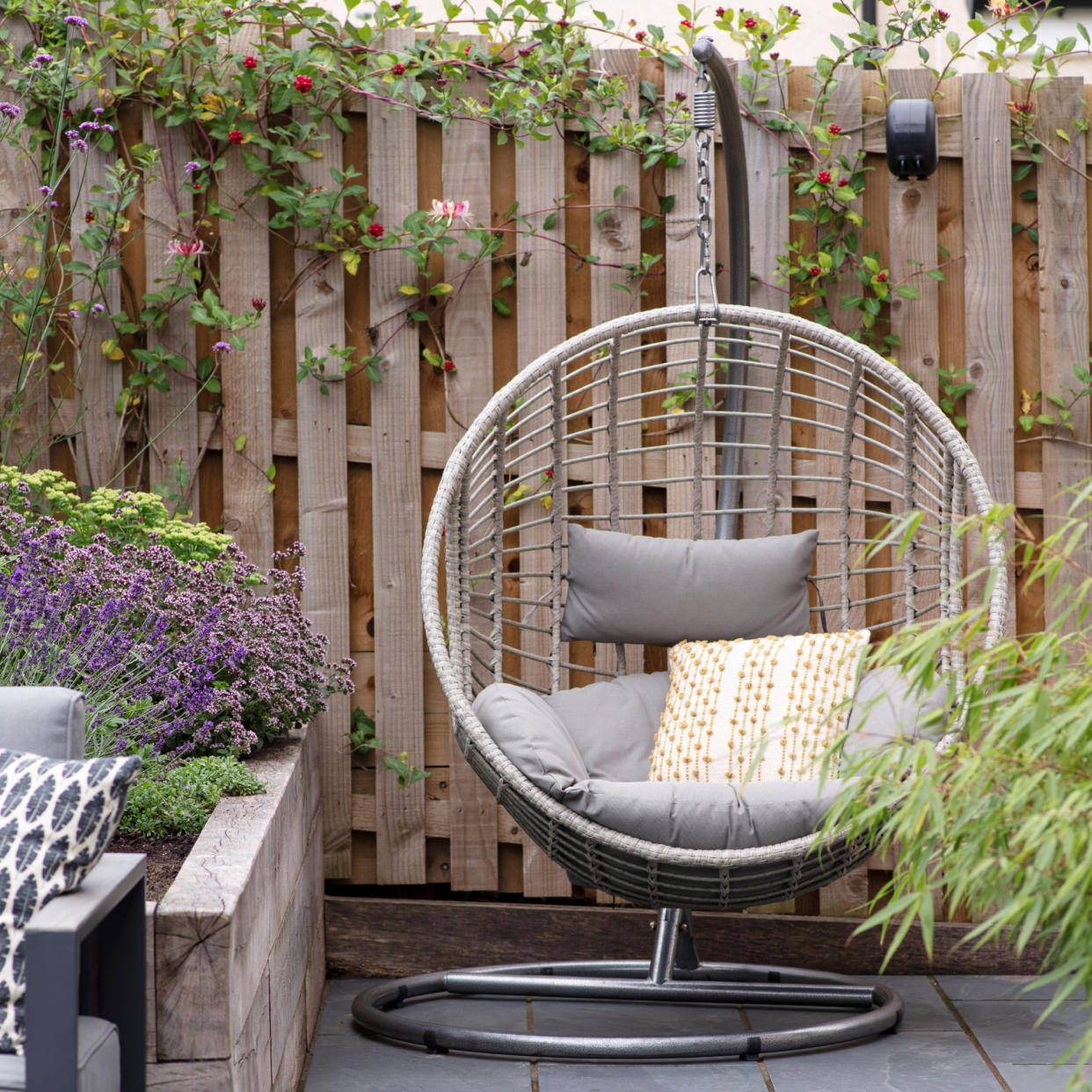 Hanging egg chair in garden patio against fencing. 