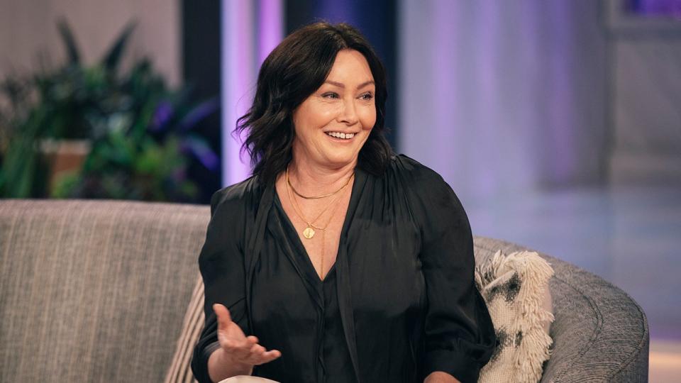 Shannen Doherty speaks on television in a black blouse