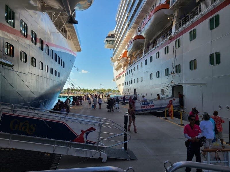 Passengers debark the Carnival Freedom, at right, on Thursday morning to spend the day in Grand Turk, after a funnel fire on the ship was brought under control. At left is Carnival's Mardi Gras. Both ships are based at Port Canaveral.