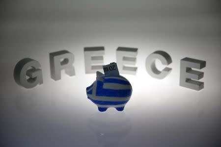 A piggybank painted in the colours of the Greek flag with a 20 euro banknote in it's slot, stands in front of letters spelling the word 'GREECE' in this picture illustration taken in Berlin, Germany June 30, 2015. REUTERS/Pawel Kopczynski