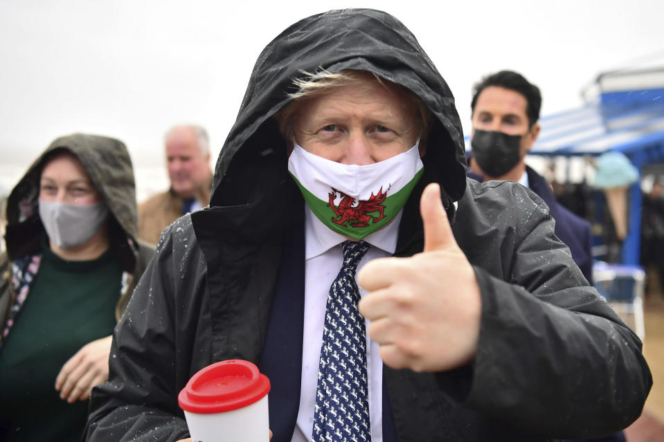 Britain's Prime Minister Boris Johnson wears a Welsh flag face mask during a visit to Barry Island, Wales, as part of the Welsh Conservative Party's Senedd election campaign, Monday, May 3, 2021. (Matthew Horwood/PA via AP)