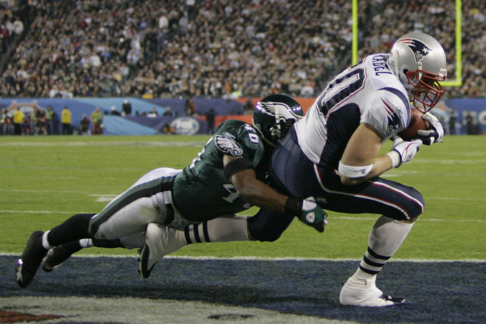 Mike Vrabel of the New England Patriots, normally a defensive linebacker, catches a pass for a touchdown from quarterback Tom Brady, in the third quarter of Super Bowl XXXIX against the Philadelphia Eagles, in Jacksonville, Florida February 6, 2005. Vrabel was in the game as an offensive receiver. Eagles safety Quintin Mikell (L) makes the unsuccessful tackle in the endzone. REUTERS/Robert Galbraith GAC