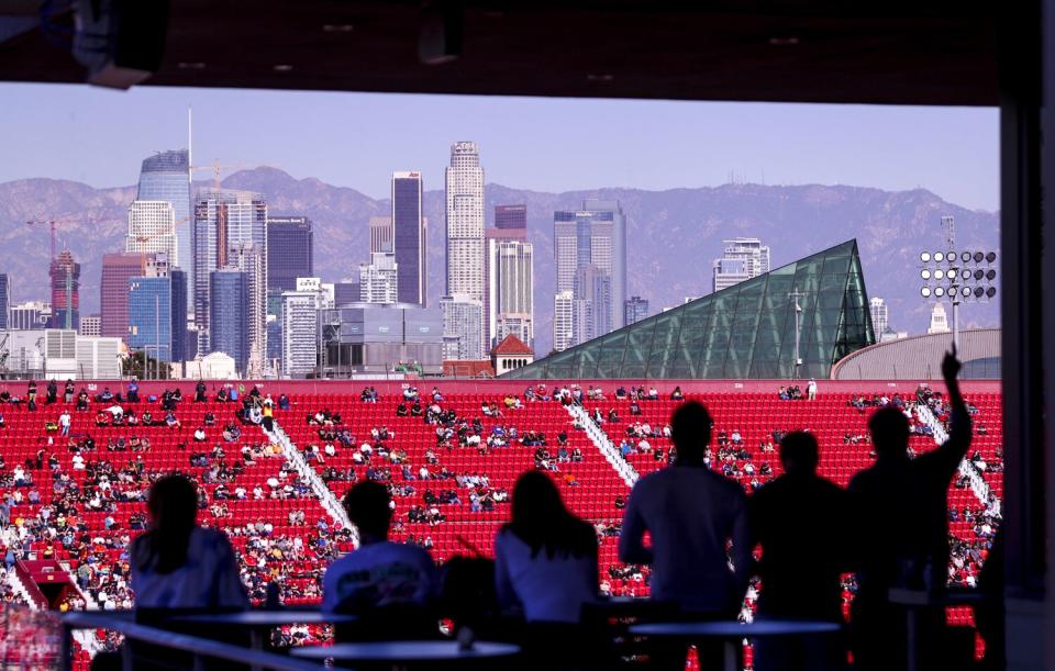 With a view of downtown Los Angeles in the background, NASCAR fans watch and cheer as racers circle the quarter-mile track.