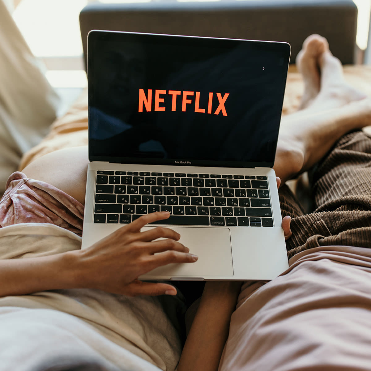 POV of couple with Netflix pulled up on laptop in bed