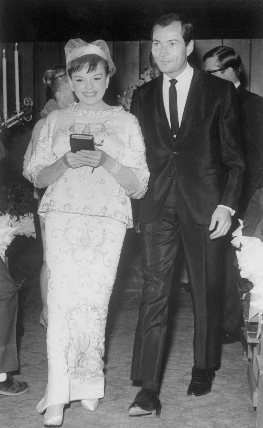 <p>After Judy Garland's divorce from her third husband, Sid Luft, was finalized, she quickly married tour manager Mark Herron at the Sahara Hotel in Vegas. However, the marriage didn't last long; Garland and Herron separated within five months. </p><p>Here, the two walk down the aisle of a Las Vegas wedding chapel at 1:30 a.m.; their marriage was witnessed by a small group of Garland's close friends. </p><p><a href="https://www.townandcountrymag.com/leisure/arts-and-culture/a30284220/judy-garland-husbands/" rel="nofollow noopener" target="_blank" data-ylk="slk:Read more: Who Were Judy Garland's Five Husbands?" class="link ">Read more: Who Were Judy Garland's Five Husbands?</a> </p>