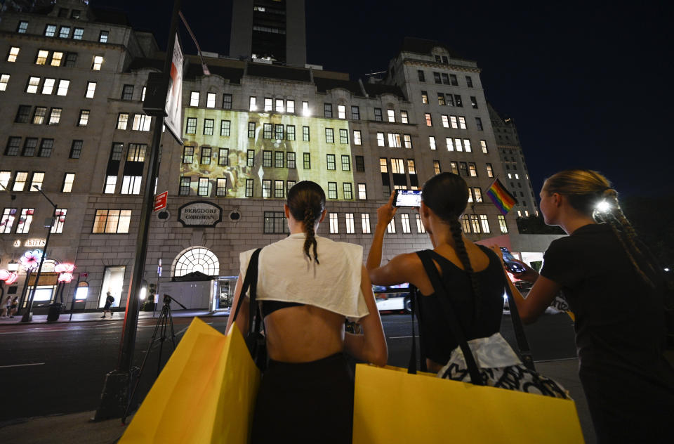 Models from the show stop by to watch themselves in the Marc Jacobs fall/winter 2021 fashion show projected on the exterior of Bergdorf Goodman department store on Monday, June 28, 2021, in New York. (Photo by Evan Agostini/Invision/AP)